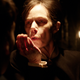 A scary figure blows dust off their hand in a spooky still from The Conjuring: The Devil Made Me Do It.